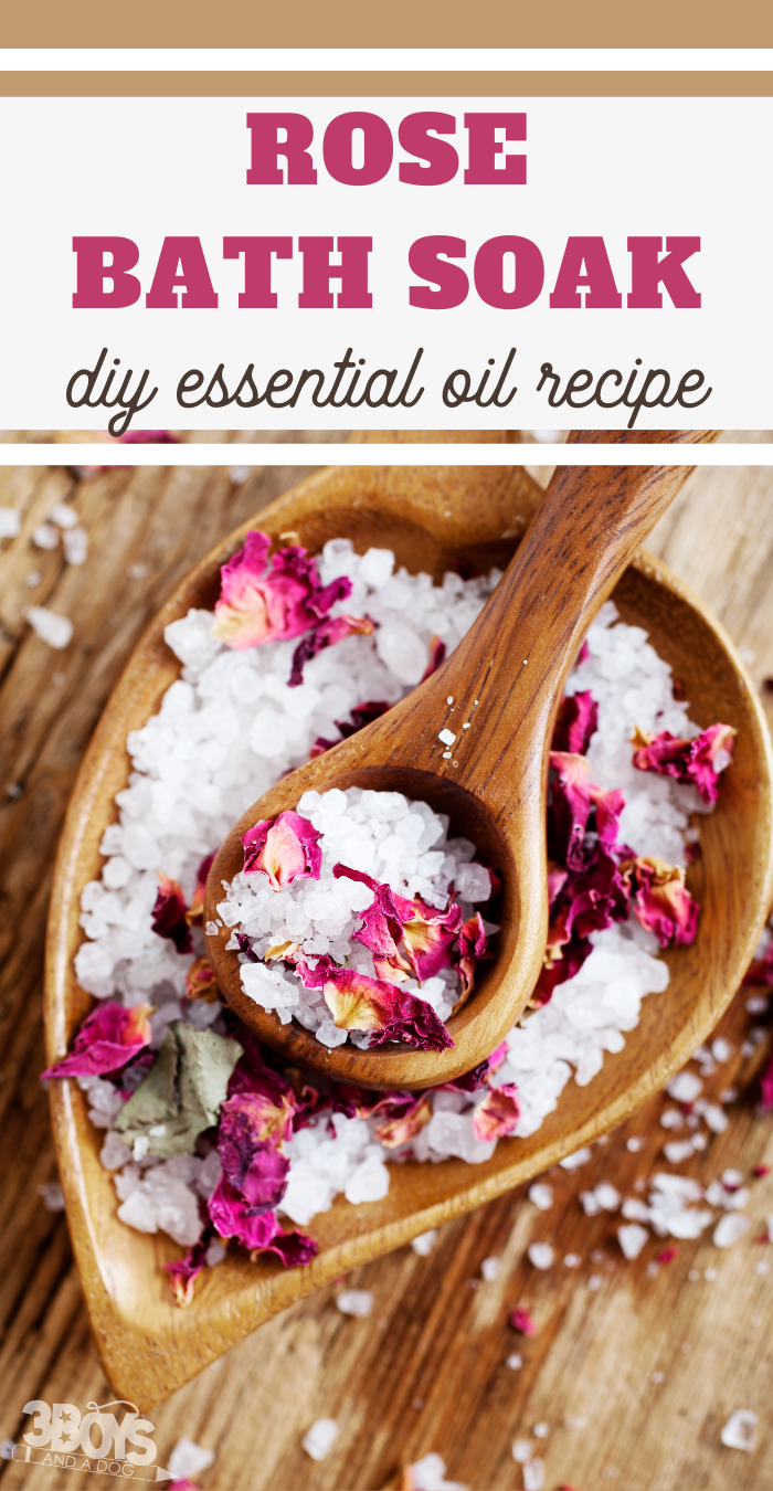 A wooden heart-shaped bowl brimming with coarse sea salt and dried rose petals, crowned by a wooden spoon holding the same blend. Text reads, Rose Bath Soak Recipe: DIY Essential Oil Delight.